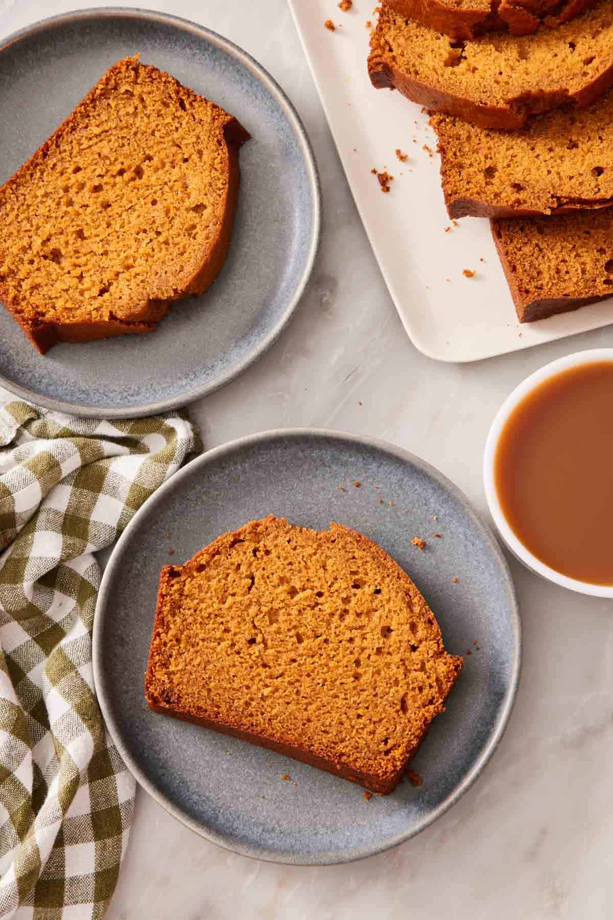 Overhead shot of slices of pumpkin bread on small plates with a cup of coffee on the side.