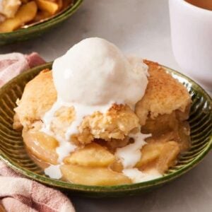 Apple cobbler in a bowl with a scoop of ice cream on top.