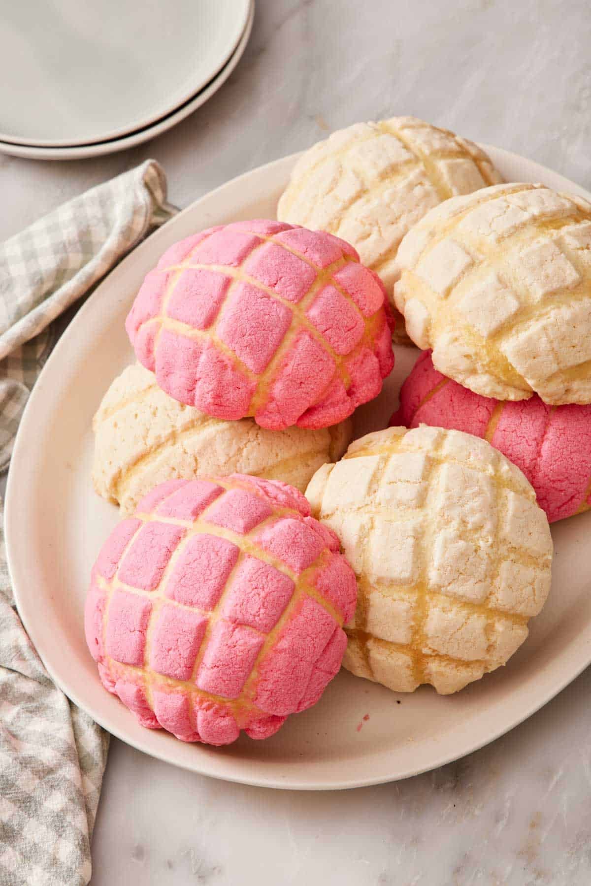 A pile of conchas on a platter on a marble countertop.