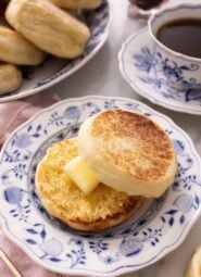 An English muffin cut in half and spread with butter on a plate